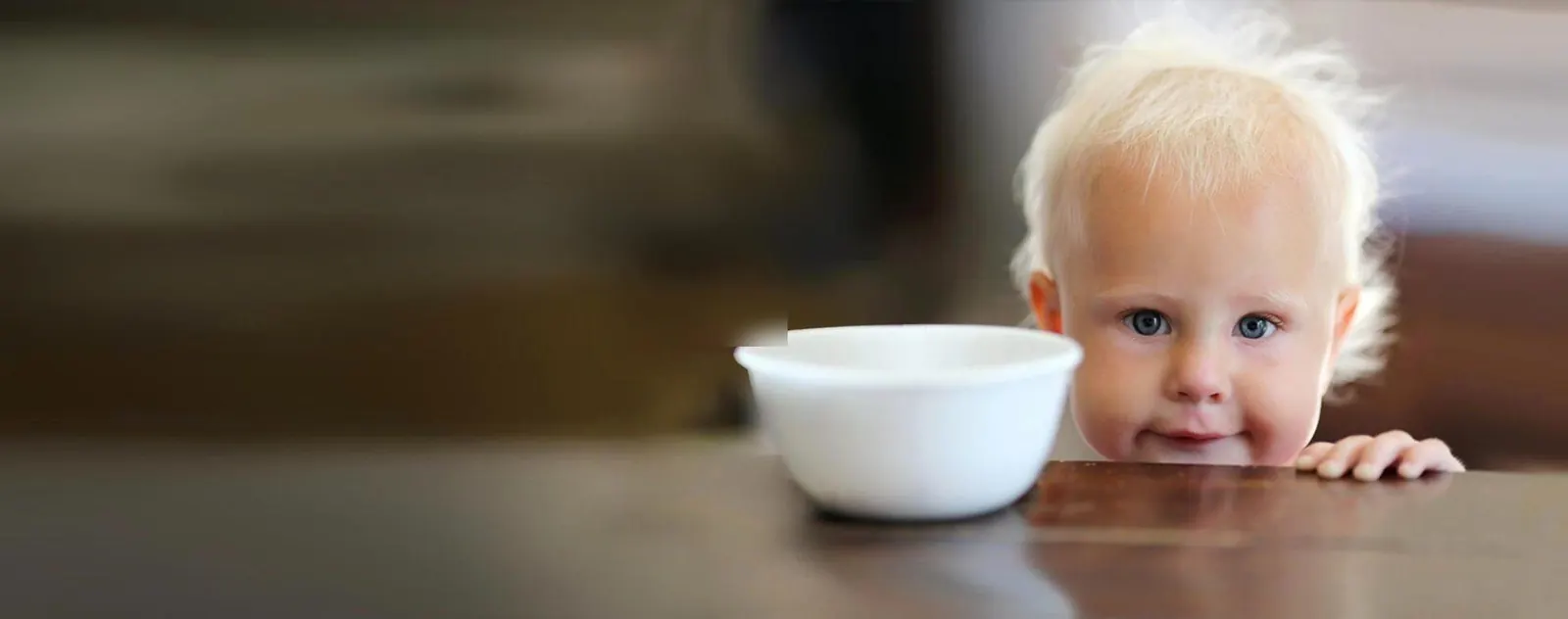 A young child peeking over at an empty bowl