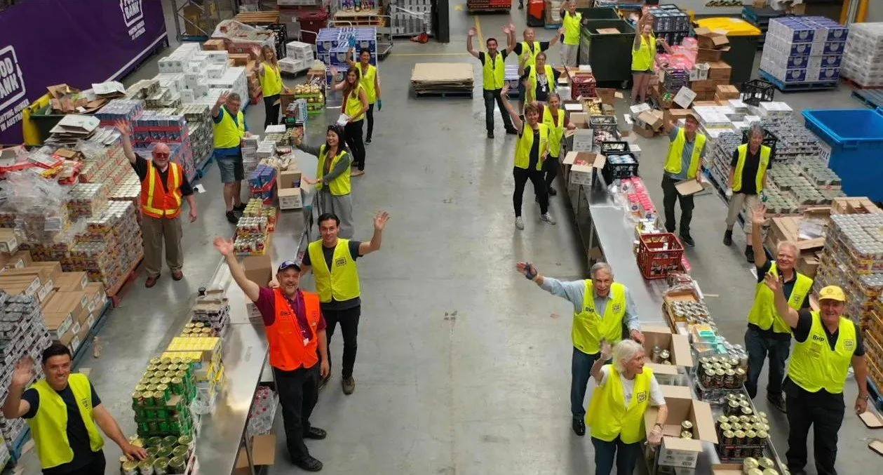 Volunteers waving from the Foodbank WA packing floor